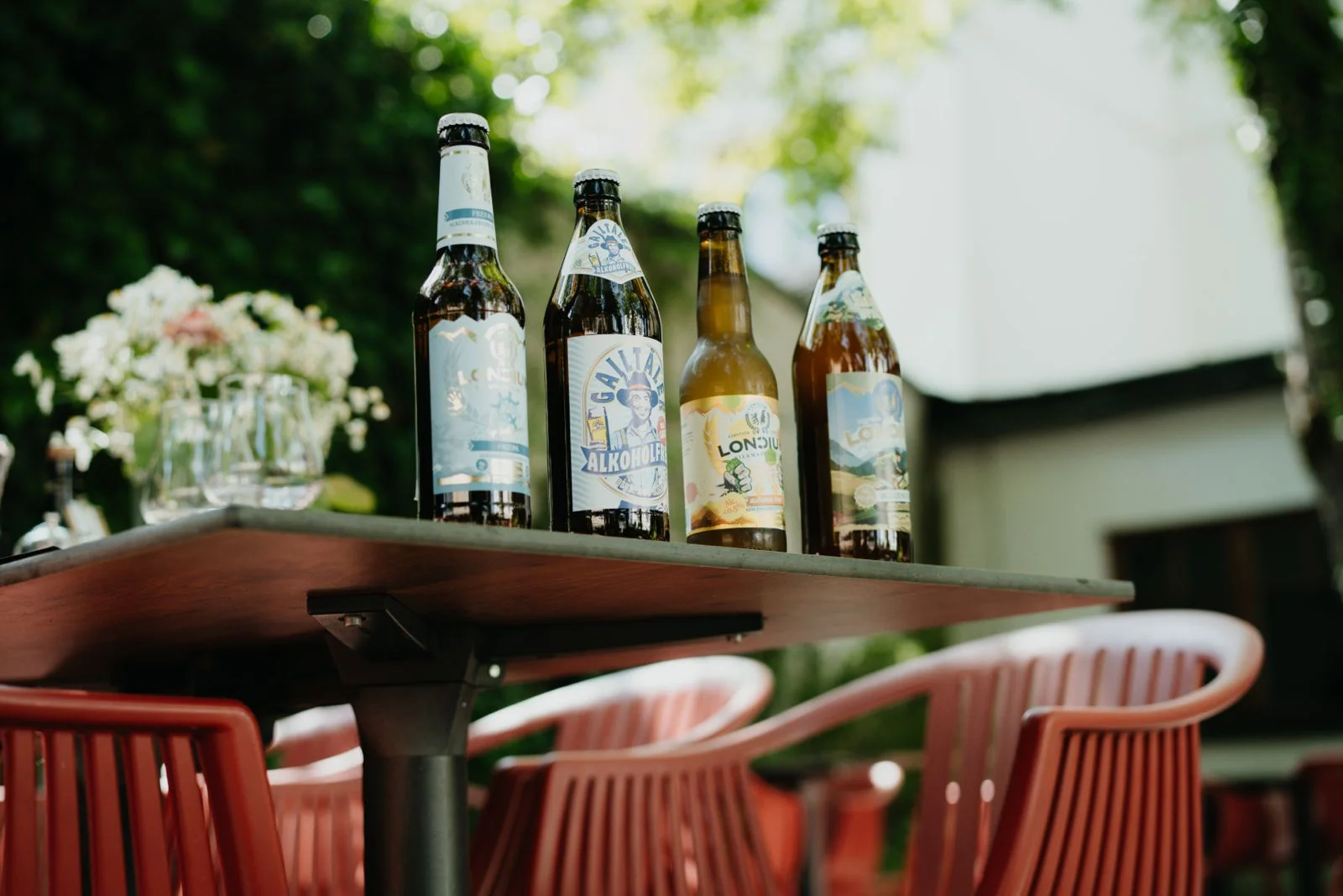 Vier alkoholfreie LONCIUM Biere auf einem Holztisch im Garten