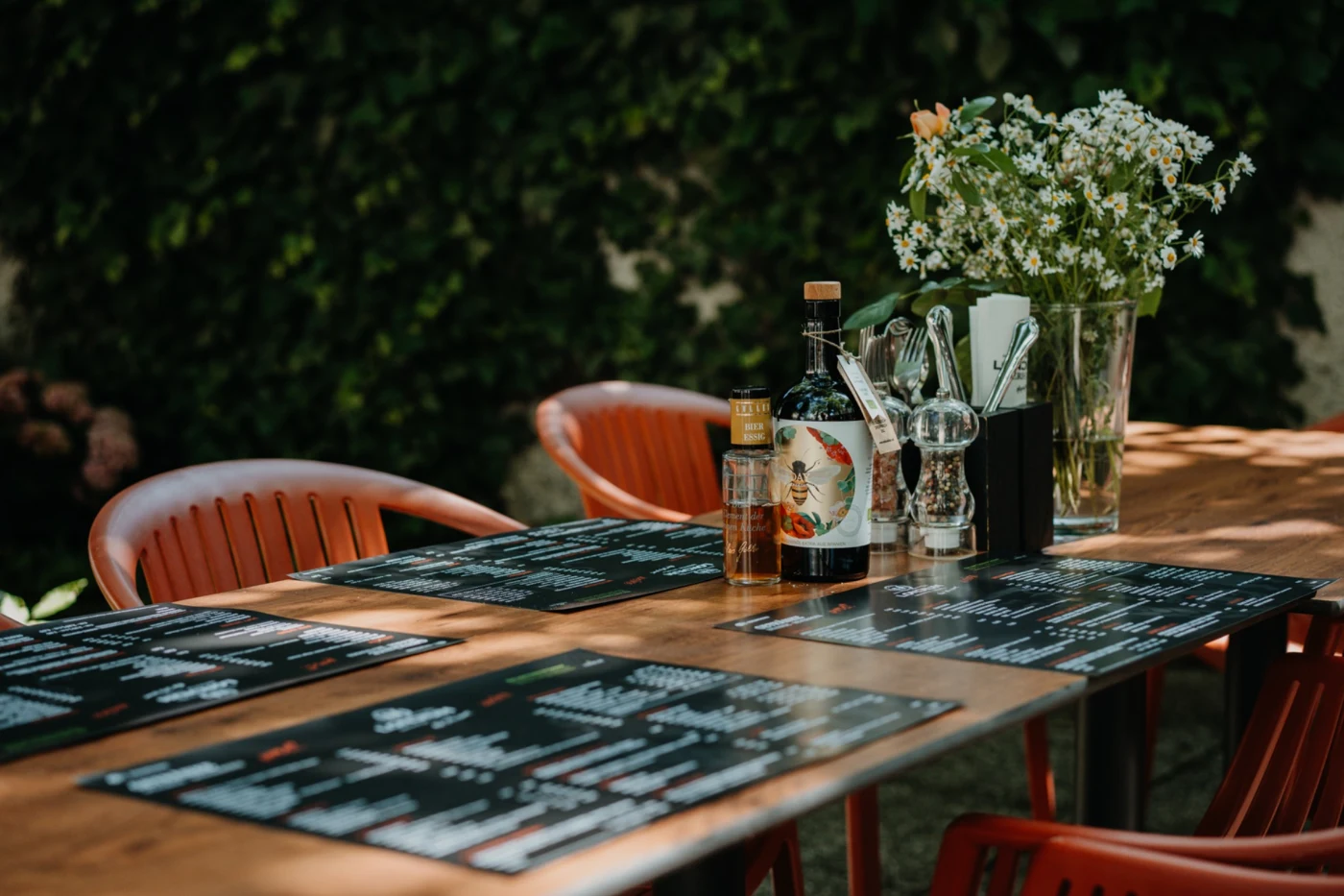 Gedeckter Holztisch im schattigen LONCIUM Biergarten