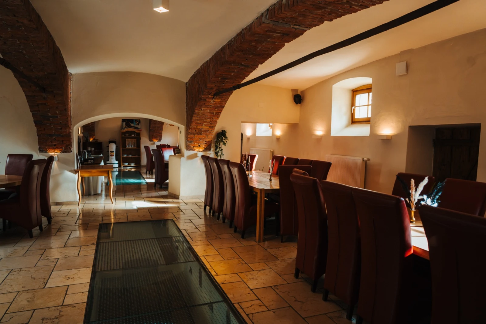 Die LONCIUM Lounge mit historischen Ziegelgewölben, Holztischen und roten Sesseln