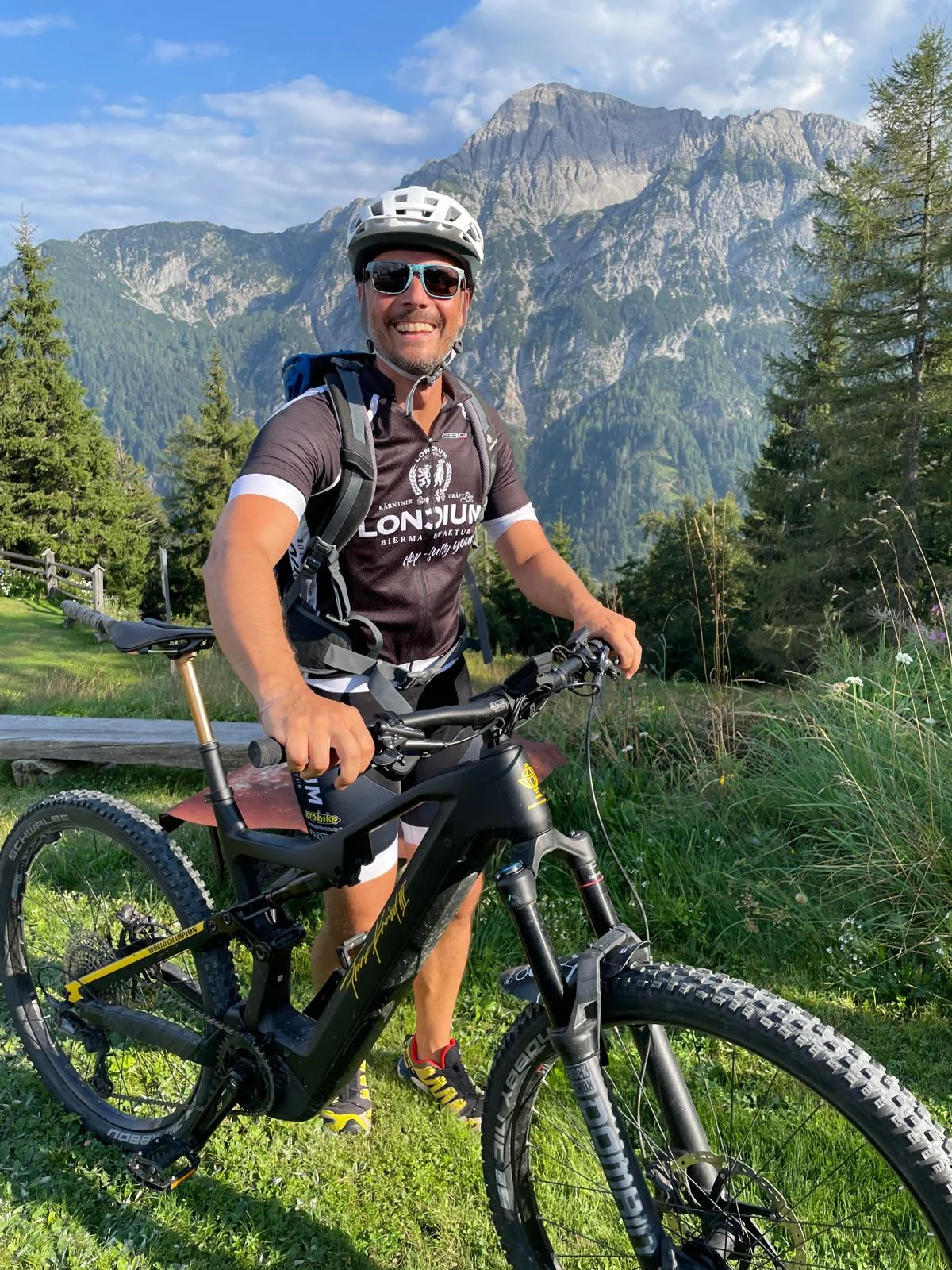 Radfahrer im LONCIUM Trikot mit Mountainbike vor einer Bergkulisse