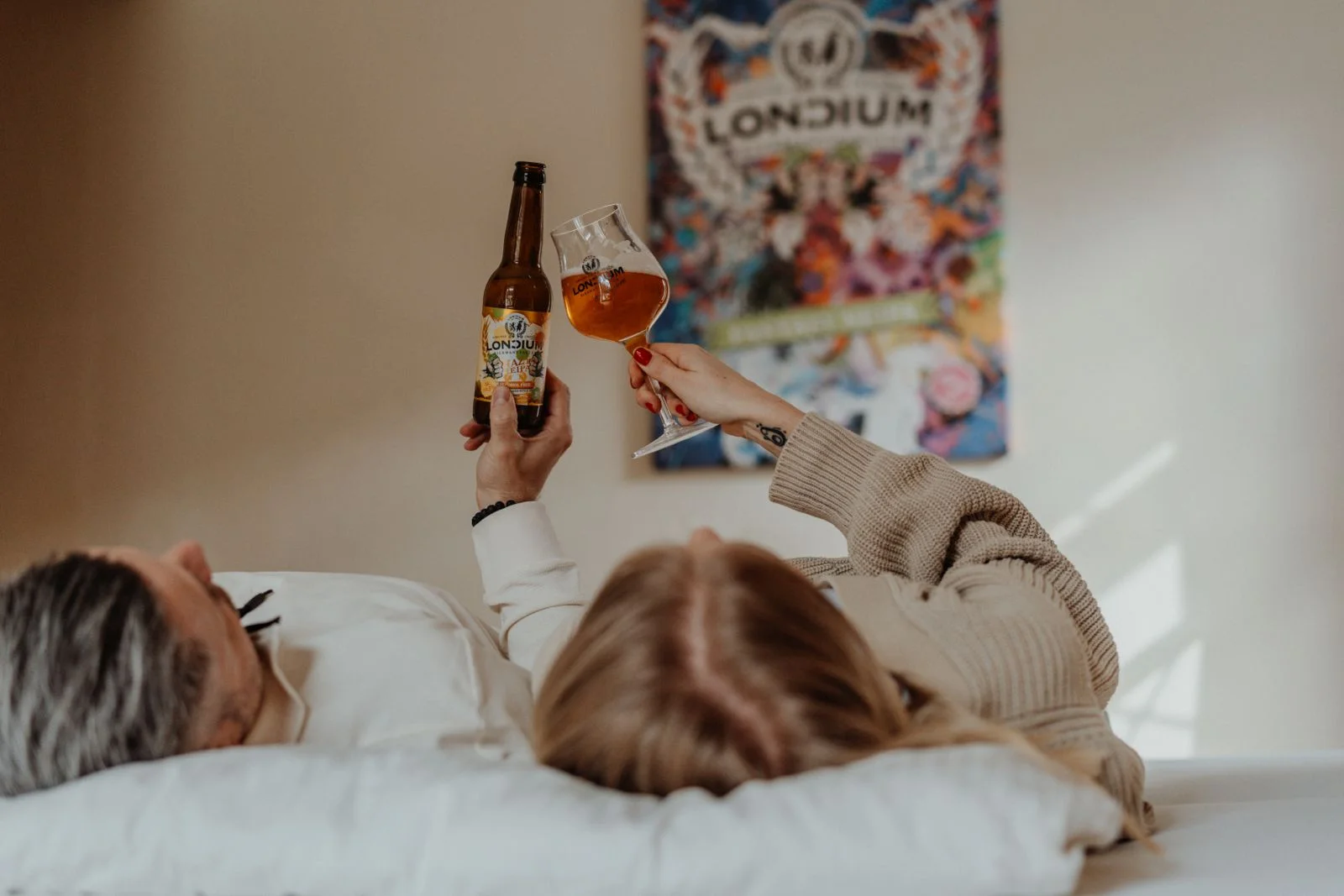 Ein Paar stößt im LONCIUM Zimmer mit Bierflasche und Bierglas an