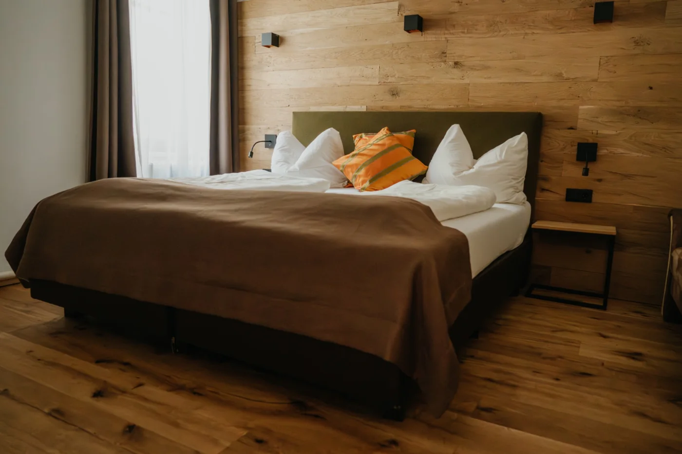 Zimmer mit Eichenholz, Doppelbett und gepolstertem Kopfteil